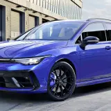 Niebieskie kombi auto Volkswagen Golf R Variant z czarnymi felgami i niebieskimi zaciskami hamulcowymi stoi przed nowoczesnym budynkiem.