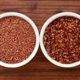 Två skålar med quinoa, en med råa röda frön och en med kokt, som visar dess höga quinoa protein.