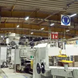 Jasne, oto opis:

Nowoczesne oświetlenie hali magazynowej zapewnia widoczność maszyn produkcyjnych i stosów kartonów.