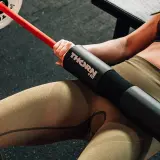 Kobieta wykonuje ćwiczenie hip thrust z gryfem i nakładką THORN + FIT. To świetny sposób na budowanie pośladków.