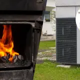 Dymiący piec i nowoczesna pompa ciepła na tle domu.