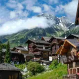 Villages de chalets en bois fleuris, montagnes enneigées en arrière-plan. Une belle idée de que faire en Suisse pour un séjour pittoresque.