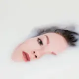Rostro de mujer sumergido en leche, parte de un ritual de doble limpieza para una piel radiante.
