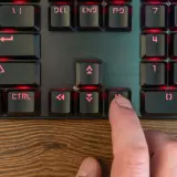 Palec naciska klawisz "Home" na podświetlanej klawiaturze programisty, co może być częścią skrótu klawiszowego.