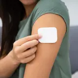 Kobieta przykleja plaster antykoncepcyjny. Przed użyciem warto zapoznać się z przeciwwskazaniami.