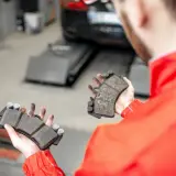 Mechanik pokazuje zużyte klocki hamulcowe, które mogą powodować syczenie przy wciskaniu hamulca.