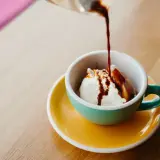 Gorące espresso zalewa kulkę lodów waniliowych w filiżance. Klasyczne lody po włosku, idealne na deser.
