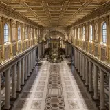 L'interno della Basilica di Santa Maria Maggiore a Roma, con il suo soffitto dorato, le colonne imponenti e i mosaici che narrano storie sacre.