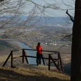 Widok z białowodzkiej góry na dolinę z rzeką i miasteczkiem. Kobieta w czerwonej bluzie podziwia panoramę.