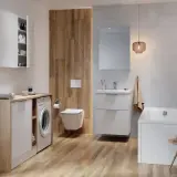 Nowoczesna łazienka z pralką, wanną i podwieszanym WC. Widoczny z tyłu złącze WC harmonijkowe.