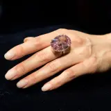 Ein großer, ovaler rosa Diamantring, der den teuersten Diamant der Welt Preis repräsentiert, wird an einer Hand getragen.