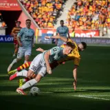 Zacięta walka o piłkę podczas meczu Jagiellonia Białystok – Piast Gliwice. Dwóch zawodników walczy o panowanie nad futbolówką na murawie.