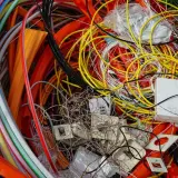 Plątanina kolorowych kabli, przewodów i białych puszek, przypominająca elektrośmieci.
