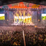 Ogromny tłum na fest festiwalu, scena rozświetlona fajerwerkami i ekranami.