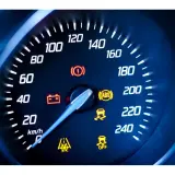 Cruscotto auto con tachimetro e spie accese: spia punto esclamativo giallo, ABS, controllo stabilità e batteria.