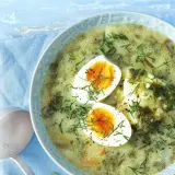 Zupa szczawiowa z jajkiem i koperkiem w misce, obok chochla.