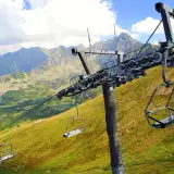 Wyciąg krzesełkowy Zakopane wita w Tatrach. Puste krzesełka wiszą na tle gór i zielonych zboczy.