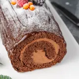 Bûche de Noël au chocolat, parfaite pour une recette génoise bûche moelleuse. Garnie de fruits rouges et de sucre glace.
