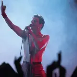Rami Malek jako Freddie Mercury śpiewa w "Bohemian Rhapsody", porywając tłum gestem i głosem.