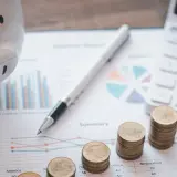 Świnka-skarbonka, monety, kalkulator i kompas na wykresach. Planowanie przyszłości po studiach finanse i rachunkowość.