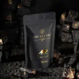 Czarna torebka z napisem "TOP ARABICA Coffee Kopi Luwak" i złotym rysunkiem zwierzęcia. To najdroższa kawa rozpuszczalna, otoczona węglem i złotymi drobinkami.