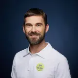 Paweł Habrat, uśmiechnięty mężczyzna z brodą, w białej koszulce polo z logo "JW TEAM".