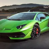 Jaskrawozielony Lamborghini Aventador SVJ na torze wyścigowym, z górami w tle.