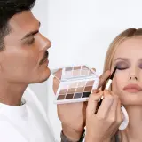 Mario Dedivanovic, maestro del maquillaje, aplica sombra de ojos a una modelo con una paleta neutra.