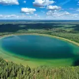 Widok z lotu ptaka na owalne jezioro o turkusowej wodzie, otoczone gęstym lasem. To najczystsze jezioro w Polsce, zachwyca przejrzystością.
