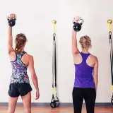 Dwie kobiety wykonują ćwiczenia z kettlebell, aby wzmocnić barki.