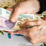 Dłonie starszej osoby liczą pieniądze. Może to być dodatek opiekuńczy po 80 roku życia, zapewniający wsparcie finansowe.
