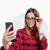 Kobieta w okularach robi selfie telefonem, zastanawiając się, czy do dowodu można mieć zdjęcie w okularach.