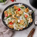 Ein üppiger italienischer Salat mit Tortellini, Kirschtomaten, Rucola und Pinienkernen, übergossen mit einer cremigen Sauce.
