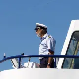 Kapitan na mostku statku, wpatrzony w dal. Zastanawia się, ile zarabia marynarz na jego stanowisku.