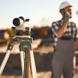 Precyzyjny niwelator na statywie czeka na geodetę. Ile geodeta bierze od punktu? To zależy od terenu i precyzji pomiaru.