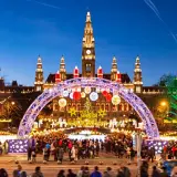 Wiedeński jarmark bożonarodzeniowy tętni życiem pod ratuszem. Kolorowe iluminacje, choinka i tłumy ludzi tworzą magiczną atmosferę.