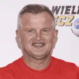 Uśmiechnięty bieleninik z TVN w czerwonej koszulce, na tle piłki nożnej z logo WOŚP.