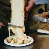 Formaggio per raclette alternativa, fuso e filante, viene raschiato da un grosso pezzo su patate bollite.