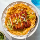 A delicious katsu don with crispy pork cutlet over rice, topped with a savory egg mixture and garnished with fresh scallions.