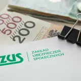 ZUS i pieniądze, być może na świadczenie mama 4 plus. Widoczne banknoty 200 i 500 zł, monety i spinacz biurowy.