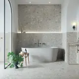 Modernes Badezimmer mit Terrazzo-Fliesen. Der Fliesentrend für Bäder zeigt sich hier in stilvoller Optik mit freistehender Wanne und Dusche.