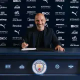 Uśmiechnięty trener Manchesteru City podpisuje kontrakt.