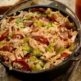 A pyszne jambalaya w żeliwnym garnku, pełne ryżu, kurczaka, kiełbasy i warzyw.
