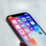 Zbliżenie na ekran smartfona z widocznymi ikonami przydatnych aplikacji, takich jak Kalendarz, Pogoda, Zdjęcia, Notatki i App Store.