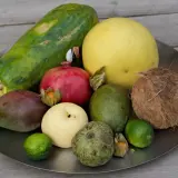 Talerz z owocami: papaja, mango, granat, pomelo, awokado, kokos, gruszka, limonki, custard apple i miechunka. Zastanawiasz się, czy można przewozić owoce w bagażu podręcznym?
