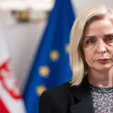 Znana posłanka KO zrezygnowała z mandatu dla kariery w biznesie prywatnym. Na zdjęciu kobieta z blond włosami, w czarnej marynarce, na tle flag Polski i UE.