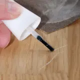 Mit einem Lackstift und Schleifpapier kleine Kratzer auf dem Laminat reparieren.