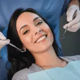 Uśmiechnięta pacjentka u dentysty, która mimo narzędzi nie wykazuje odruch wymiotny.