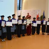 Absolwenci w togach i biretach odbierają dyplomy. Uroczystość wręczenia tytułów licencjat.