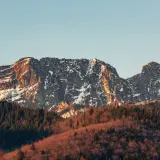 Giewont ośnieżony, z krzyżem na szczycie, w złotym świetle zachodzącego słońca. Czy ciężko wejść na Giewont? Widok zapiera dech w piersiach.